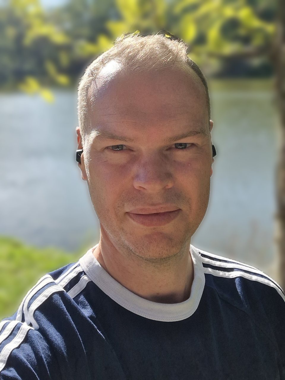 Porträt von Sascha Bohn, lächelnd im Freien an einem See